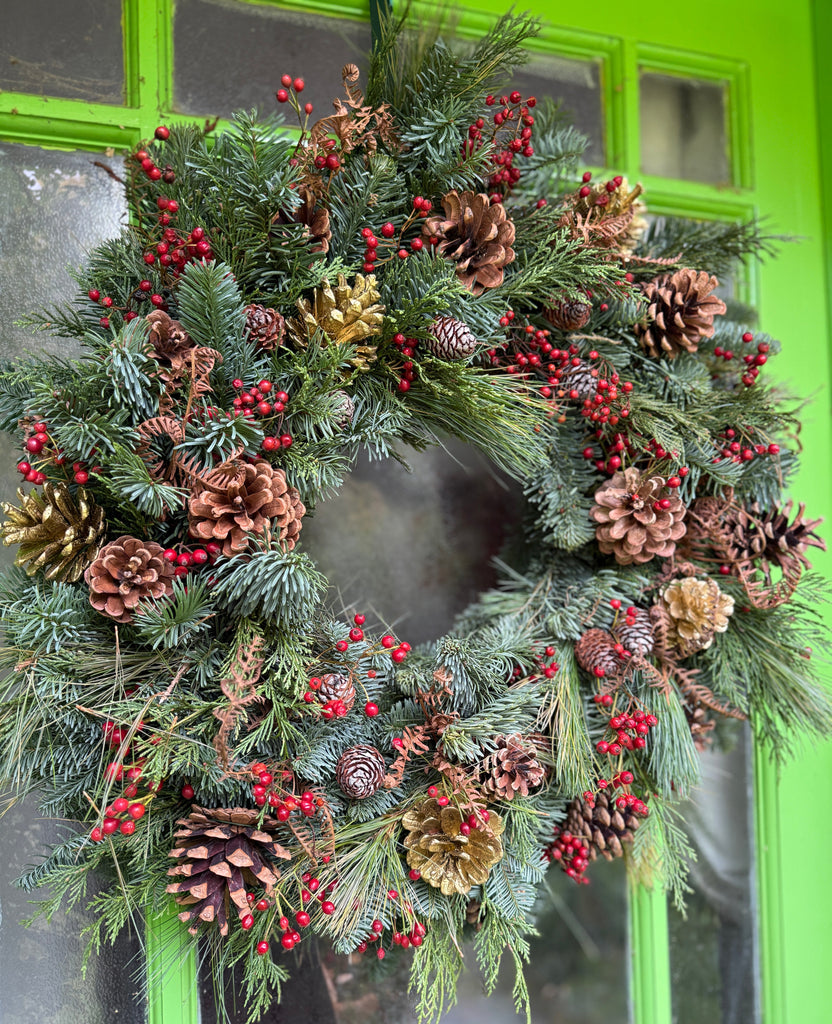 Christmas wreath with pine cones and berries on a green door